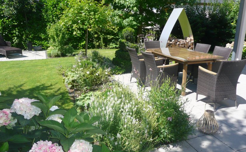 Möblierte Terrasse in klassischem Garten mit Rasenfläche und Blumenbeeten mit Hortensien und weißem Lavendel