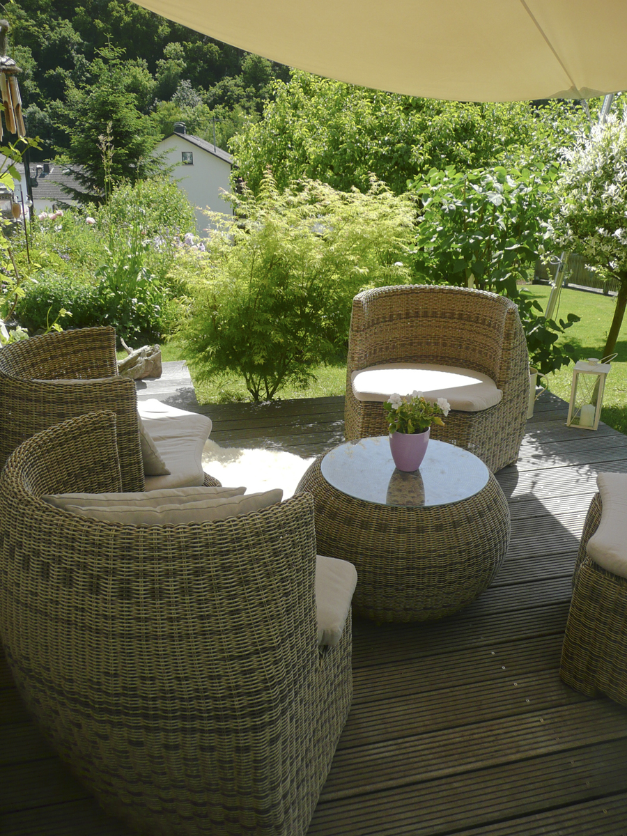 Terrasse mit Sonnensegel im umgestalteten Cottage Garten, Blick auf blühende Sträucher