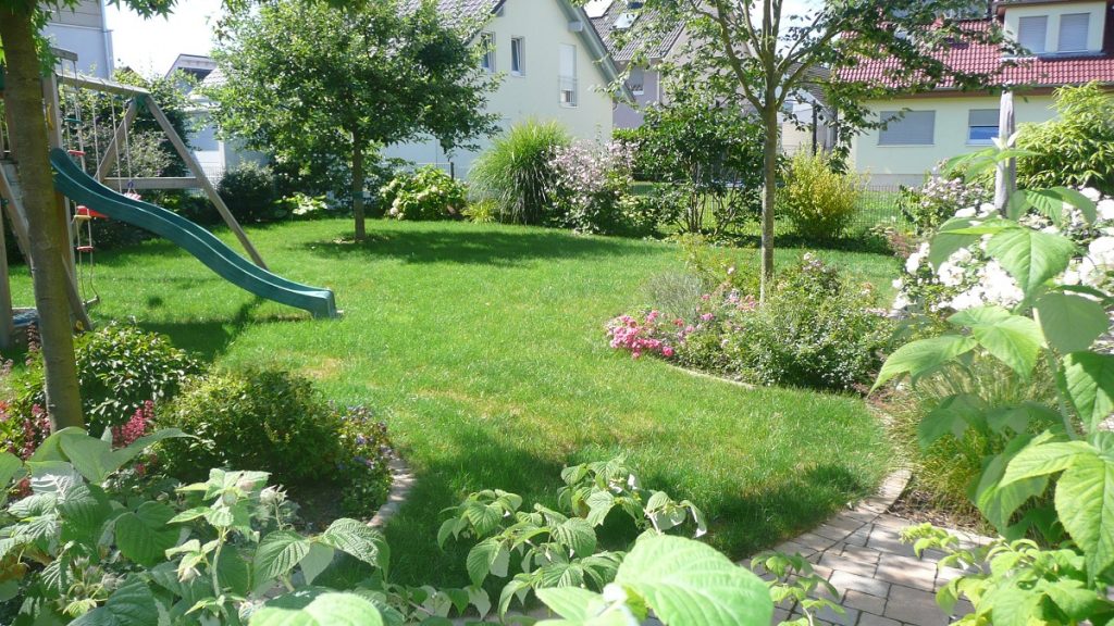 Familiengarten in Bruchköbel. mit Staudenbeeten, Rasen und Kinderspielbereich