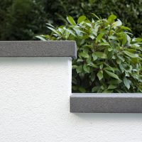 Neugestaltung eines modernen Gartens in Bad Homburg - Grundstücksmauer mit Abdeckung aus grauen Rinnit Steinplatten