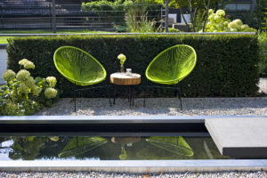 Wasserbecken mit Rahmen aus Edelstahl und Rinnit Trittplatte. Die Umrandung aus Kies bepflanzt mit weißer Bauernhortensie. Moderne Gartenmöbel für das neue Design im Garten.