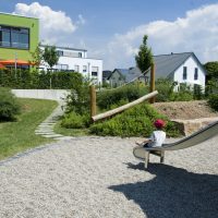 Kita Kunterbunt Langenselbold | Ansicht Spielplatz und Kind auf Rutschbahn