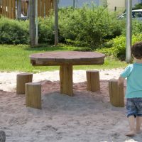 Kita Kunterbunt Langenselbold | Kind auf Sandspielplatz mit Sitzbereich aus Holz