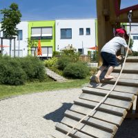 Kita Kunterbunt Langenselbold | Aussenanlage Spielplatz - Kind auf Kletterburg aus Holz