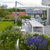 Planung und Gestaltung eines modernen Gartens in Hofheim - Die Terrasse ist modern gestaltet, mit Wasserbecken und Trittplatten, sowie einem Quellstein im Becken. Die Staudenbeete, bepflanzt mit Salbei, weißem Lavendel und Gräsern, umranden die Terrasse.