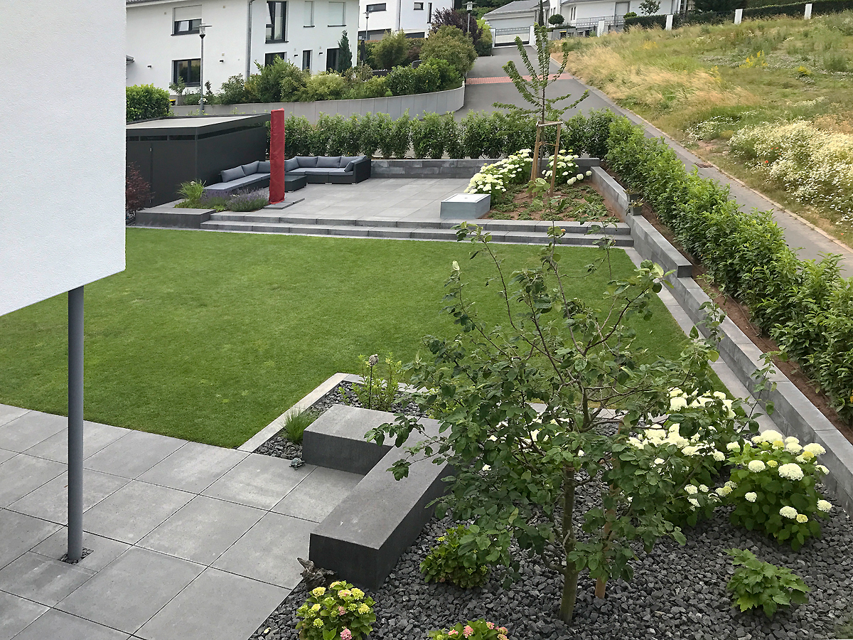 Ansicht von oben. Moderner Garten mit erhöhter Sitzfläche und lockerer Bepflanzung mit weissen Hortensien und Obstbäumen.